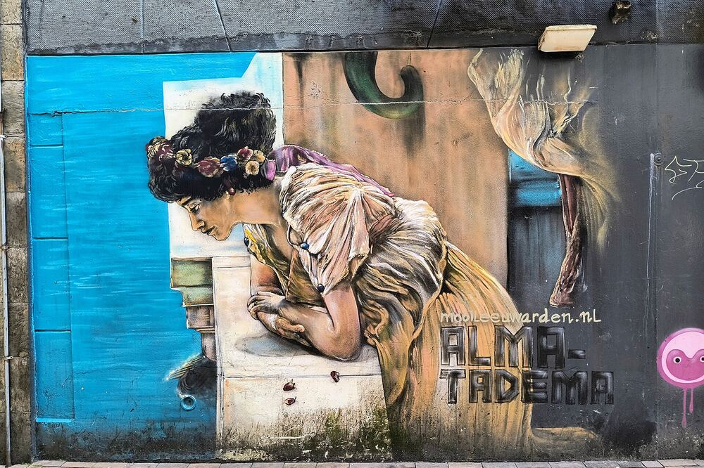 Grote muurschildering van een lezende vrouw naar Alma-Tadema op een gevel in Leeuwarden